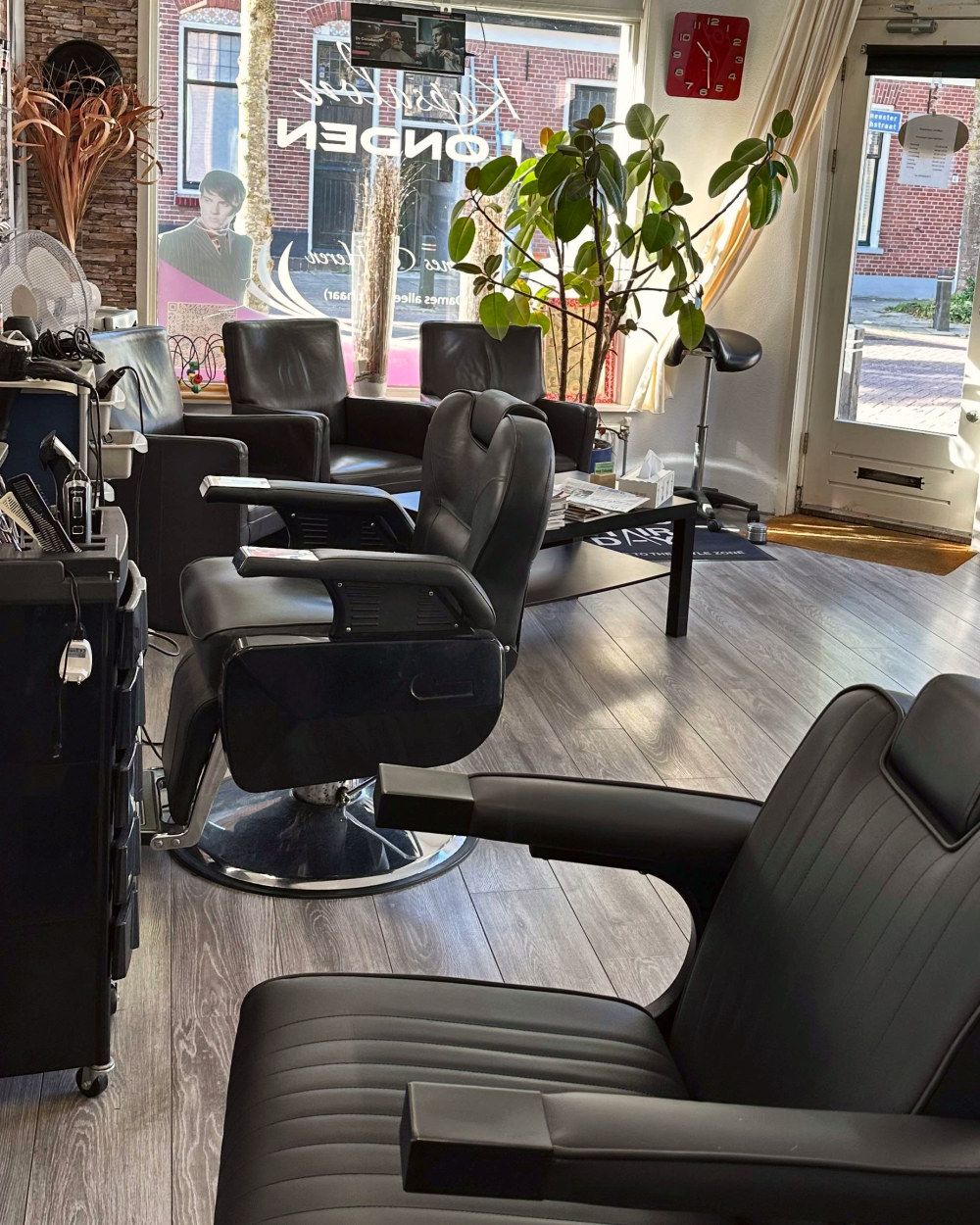 Uitzicht vanuit een kappersstoel bij Kapsalon Londen naar het raam en de open deur