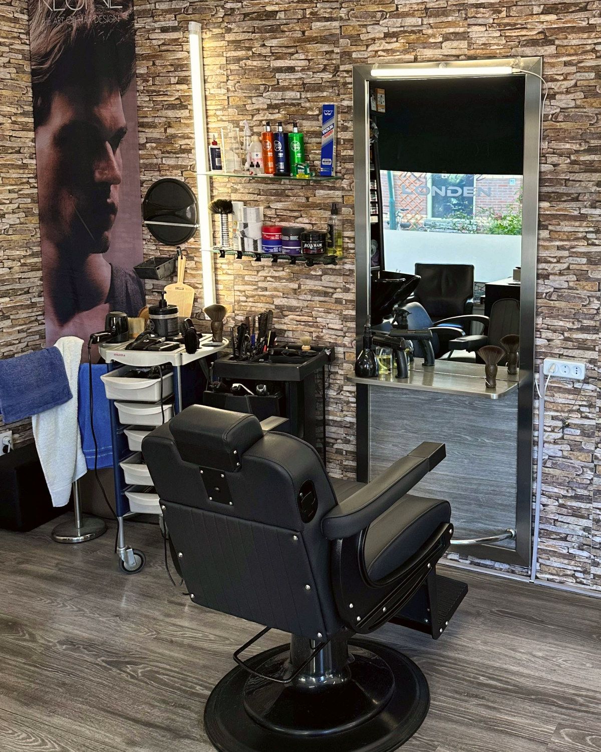 Zwarte kappersstoel voor een verlichte spiegel bij Kapsalon Londen